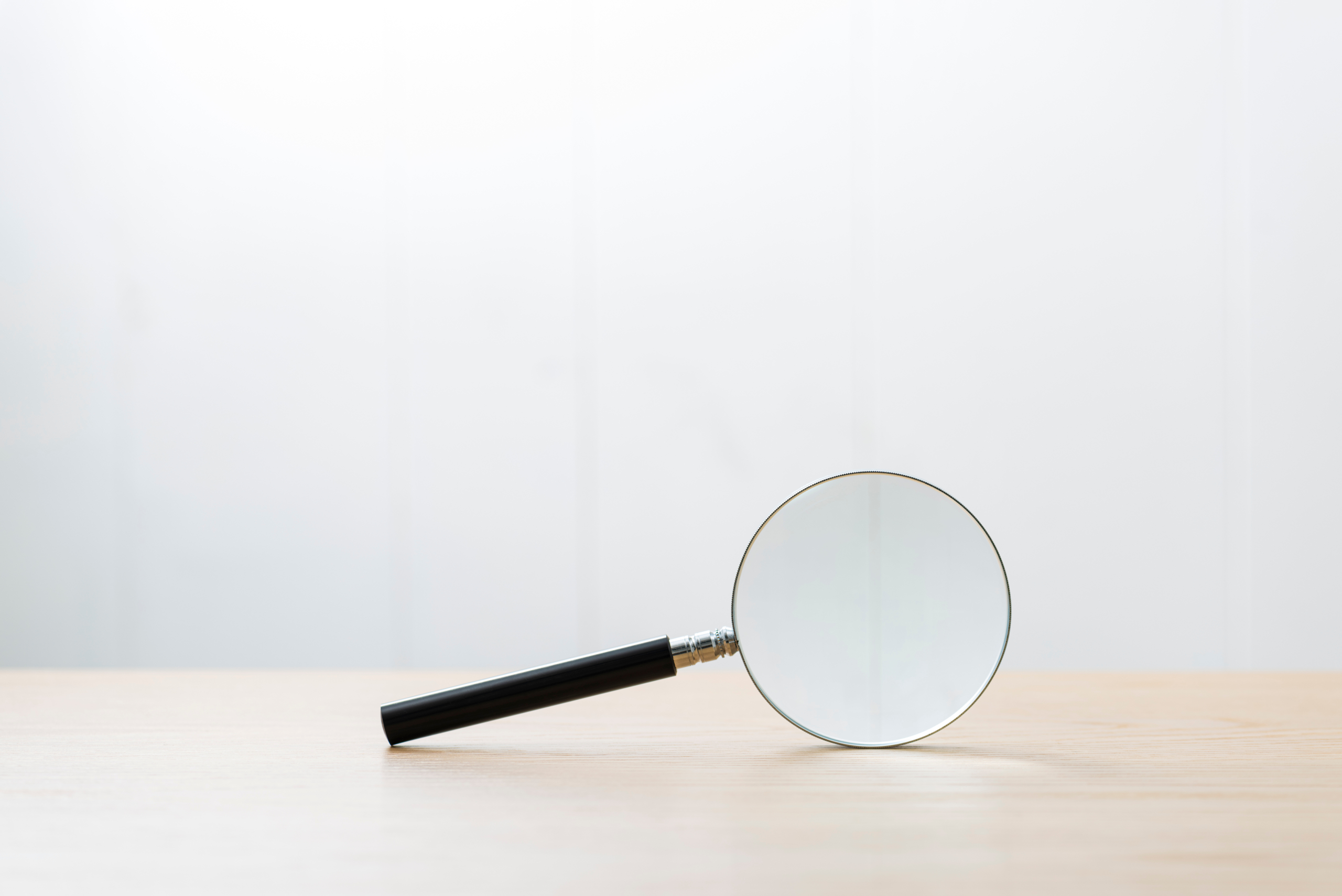 木製のテーブルに置かれた拡大鏡。探求、調査、分析のイメージ。